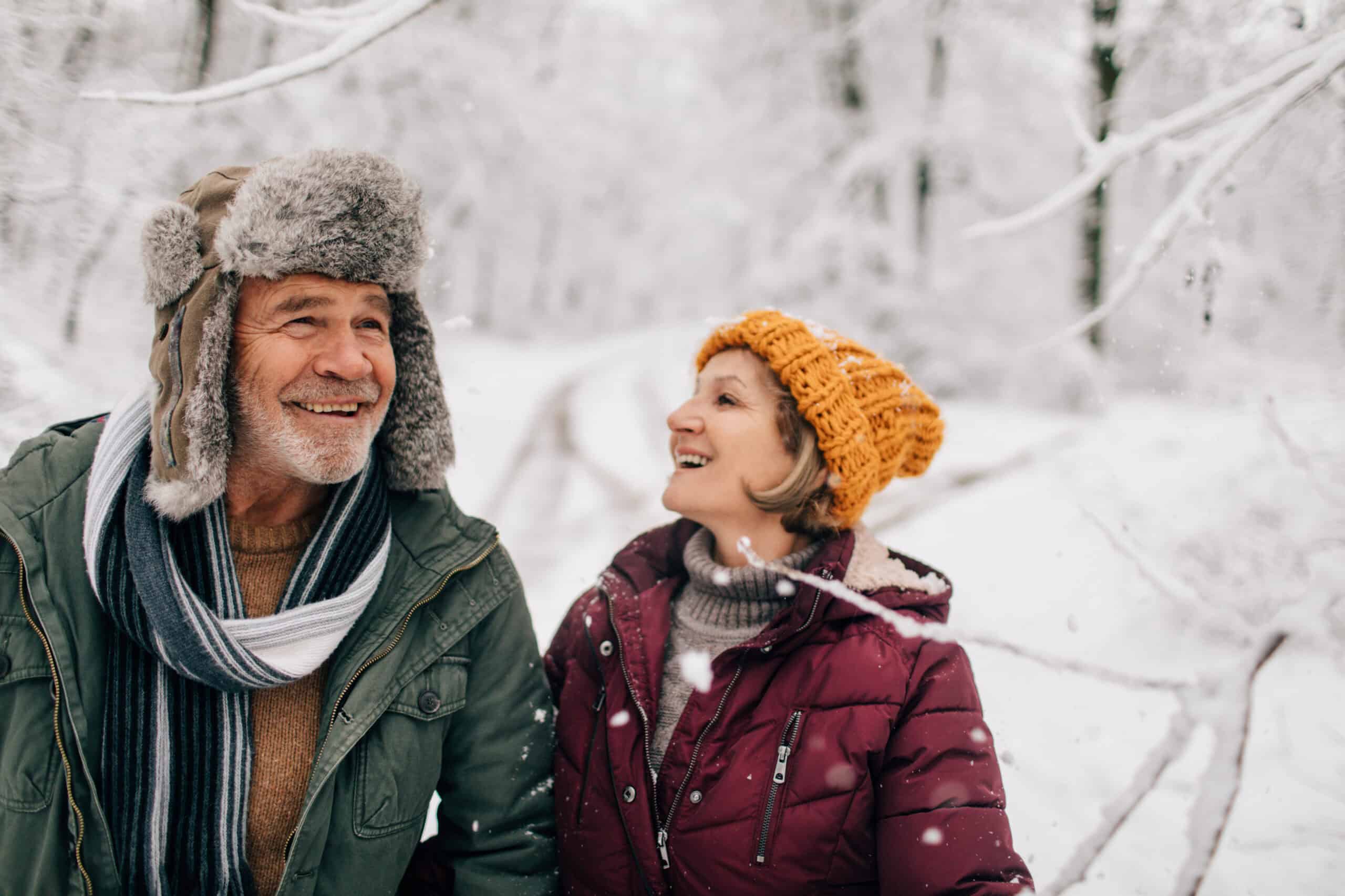 Photo of an elderly couple who enjoy walking together on a cold snowy day while holding hands