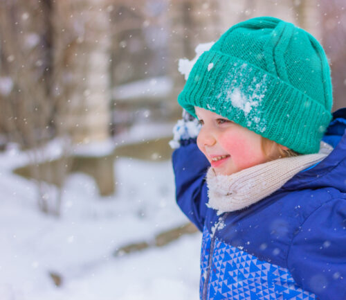 cute cheerful boy playing snowballs on a snowy street