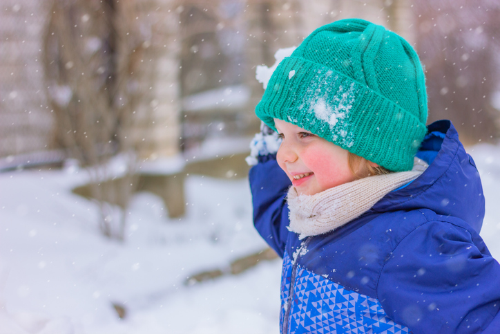 cute cheerful boy playing snowballs on a snowy street