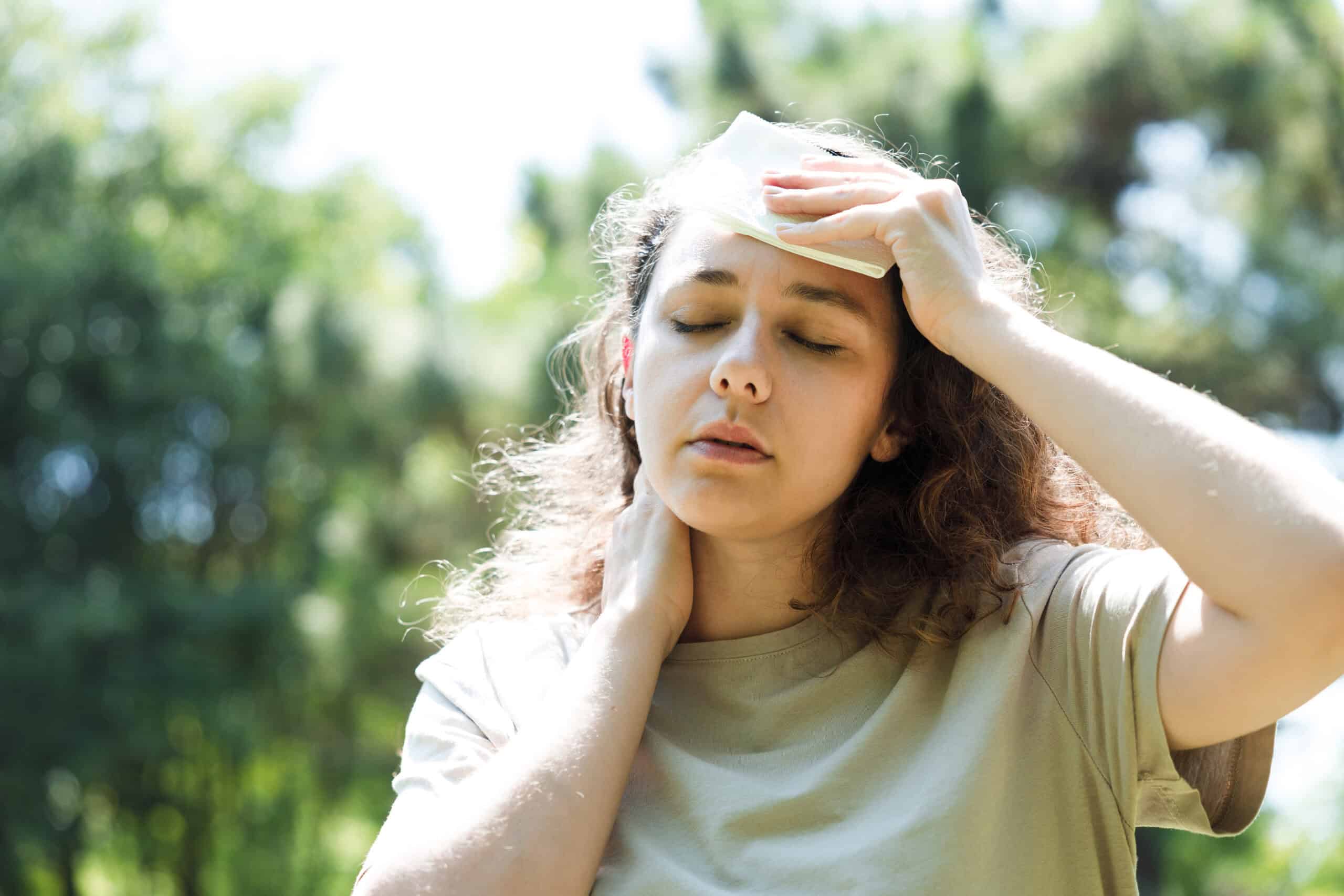Young woman having hot flash and sweating in a warm summer day