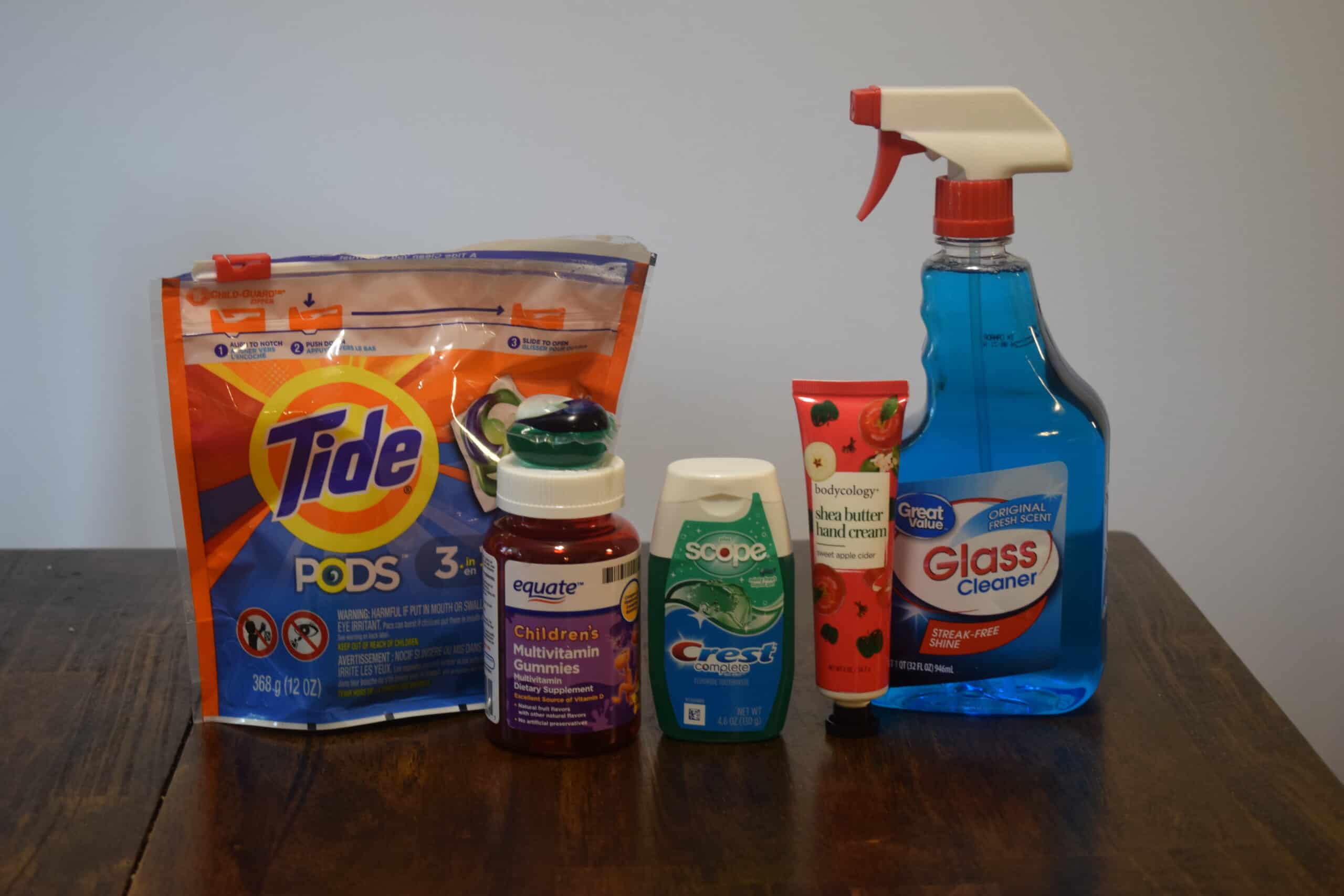 Tide pods, gummy vitamins, toothpaste, lotion, and window cleaning liquid in a row