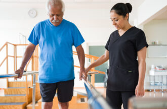 Senior man giving small steps between parallel bars