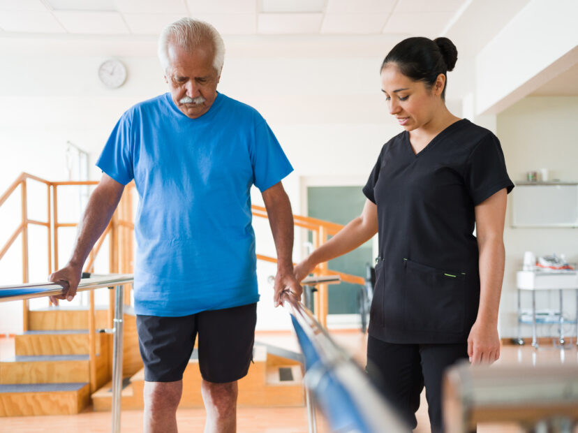 Senior man giving small steps between parallel bars