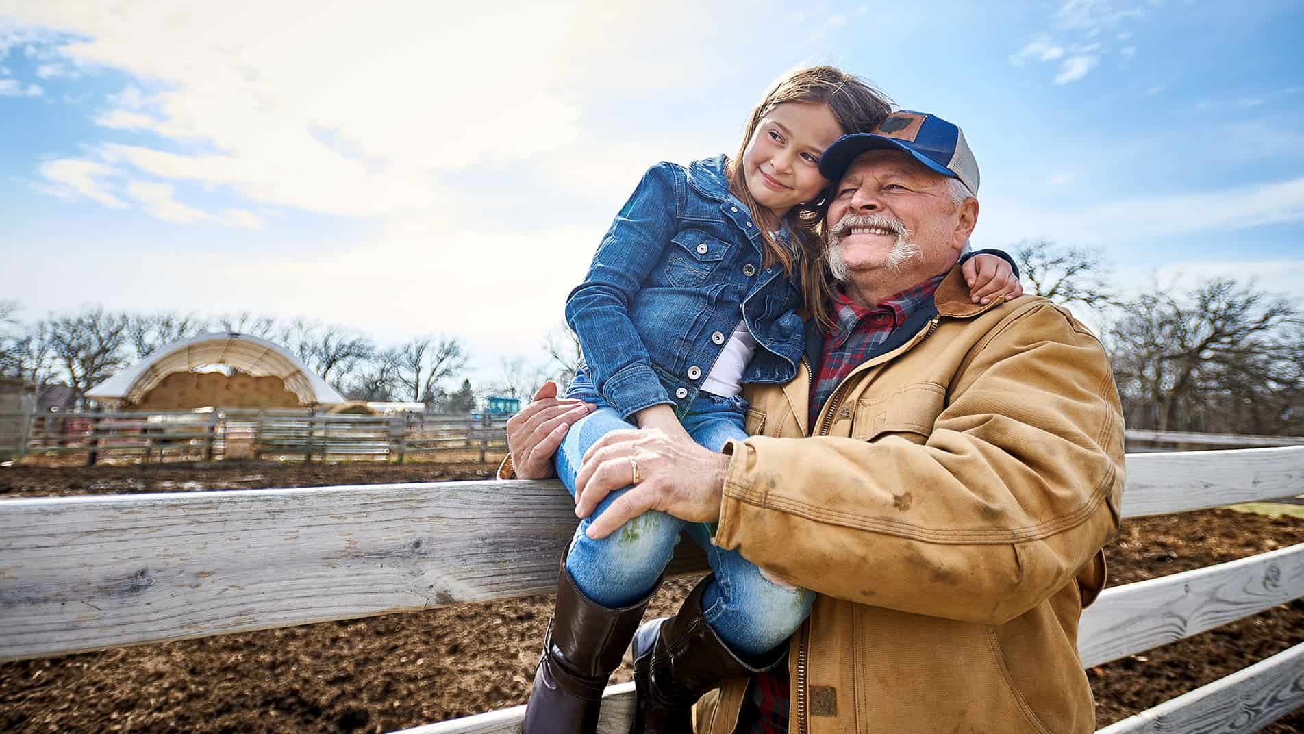 Grandfather hugging grandaughter on his farm