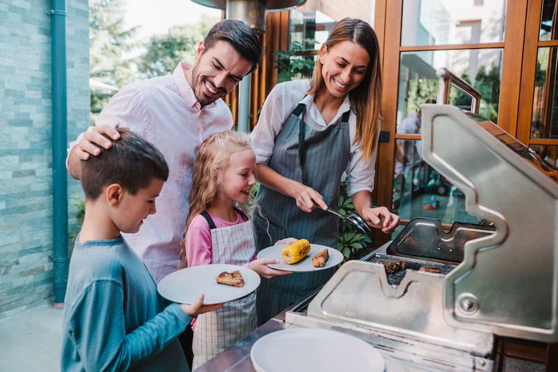 Cheerful mother making barbecue for her family in the backyard.