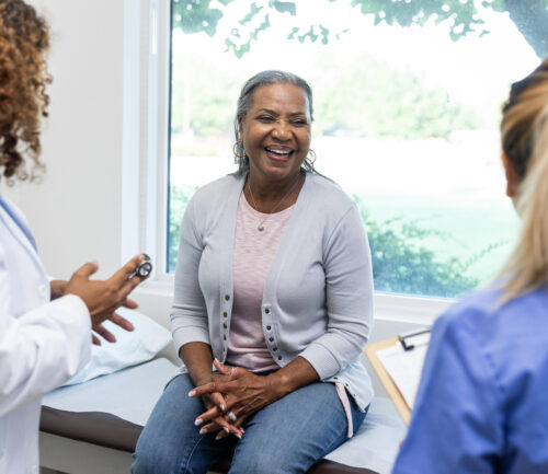 Mature female patient smiles while the healthcare professionals ask her about her family