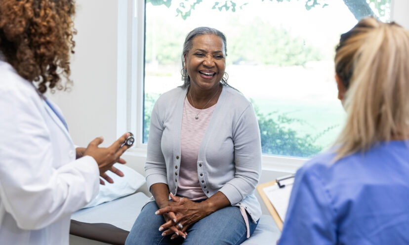 Mature female patient smiles while the healthcare professionals ask her about her family