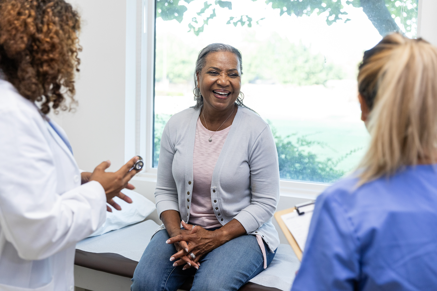 Mature female patient smiles while the healthcare professionals ask her about her family