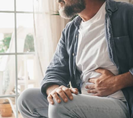 Man holding his stomach in his home.
