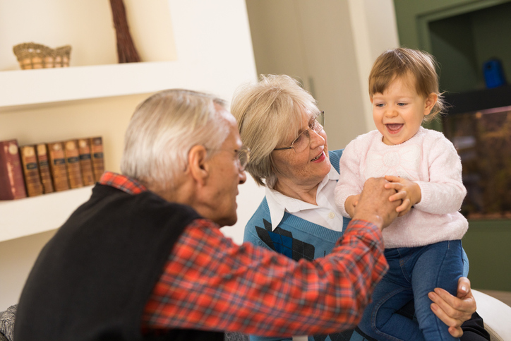 Smiling senior couple playing with their grandchild at home