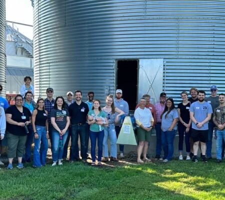 group poses in front of farm