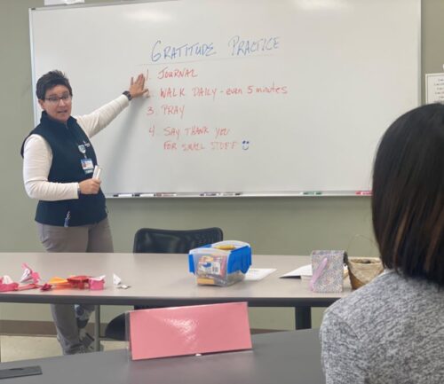 Julie Manuel teaches person about gratitude in front of a whiteboard