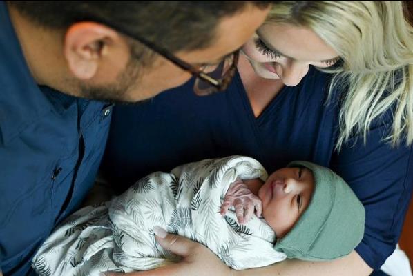 A mother and father hold their newborn.