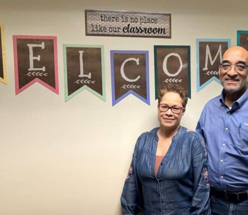 Ron and Krista Mainess pose in front of a welcome sign