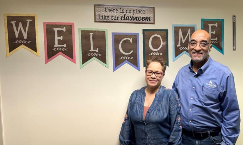 Ron and Krista Mainess pose in front of a welcome sign