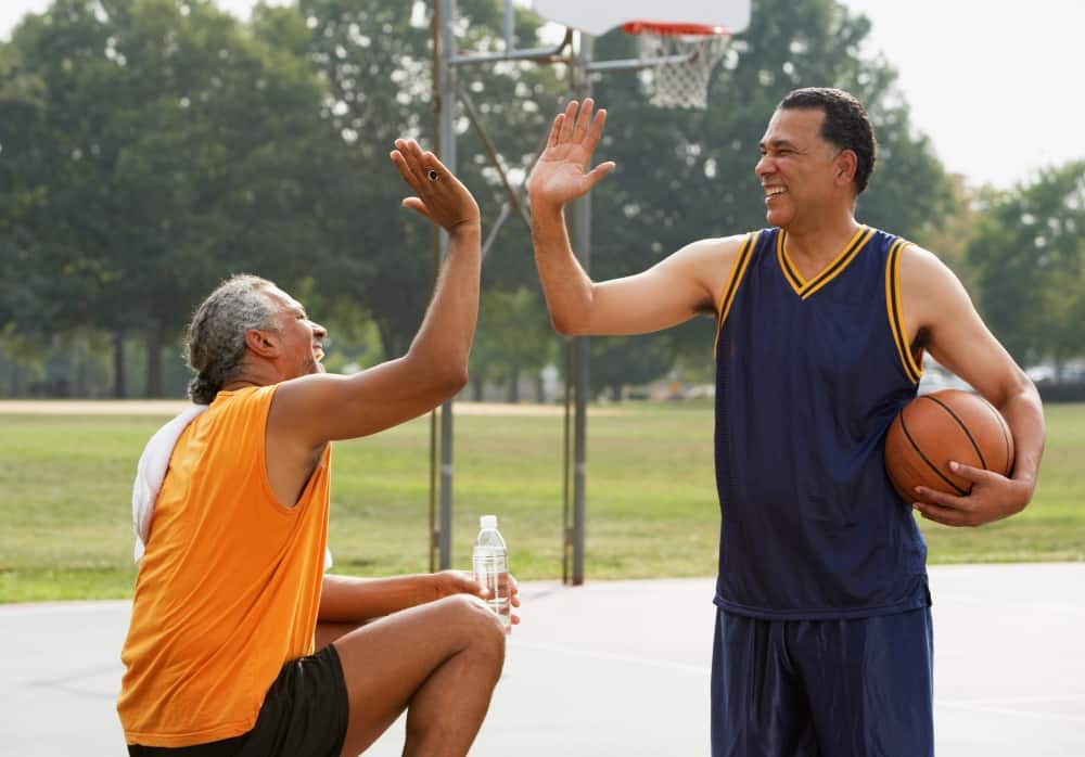Two men high-fiving at a basketball court outside
