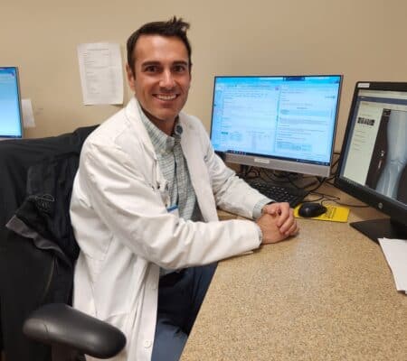 Dr. Blake Daney smiling at camera in front of computer