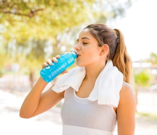 woman drinking a sports drink outside