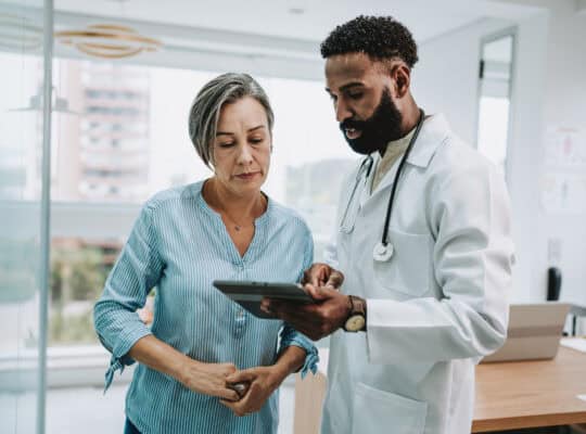 Doctor talking to patient holding digital tablet