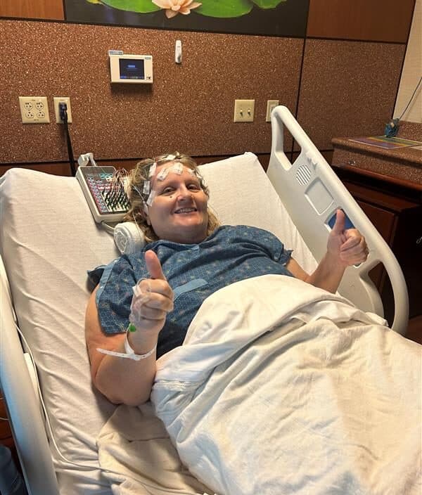 patient giving thumbs up in a hospital bed after brain tumor surgery.