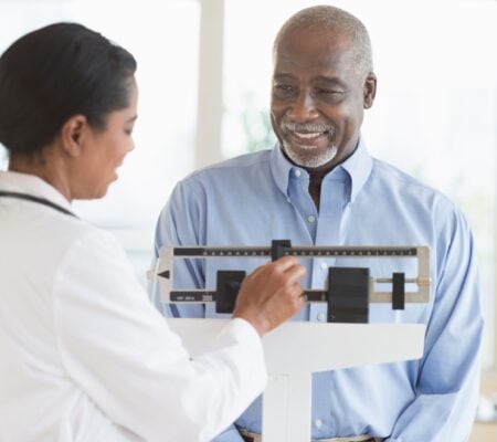 Man on scale while doctor checks his weight