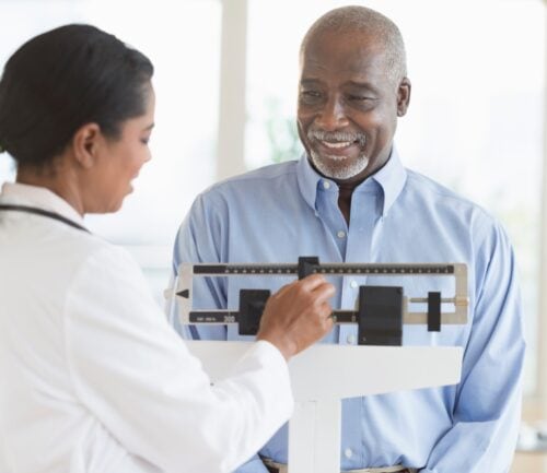 Man on scale while doctor checks his weight