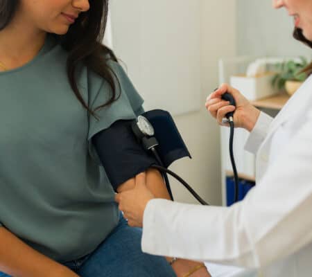 Closeup of a doctor measuring blood pressure of young woman during medical check-up