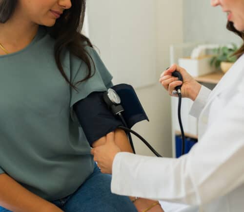 Closeup of a doctor measuring blood pressure of young woman during medical check-up
