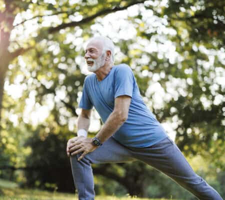 Shot of a senior man standing alone and stretching during his outdoor workout