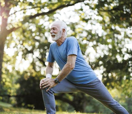 Shot of a senior man standing alone and stretching during his outdoor workout