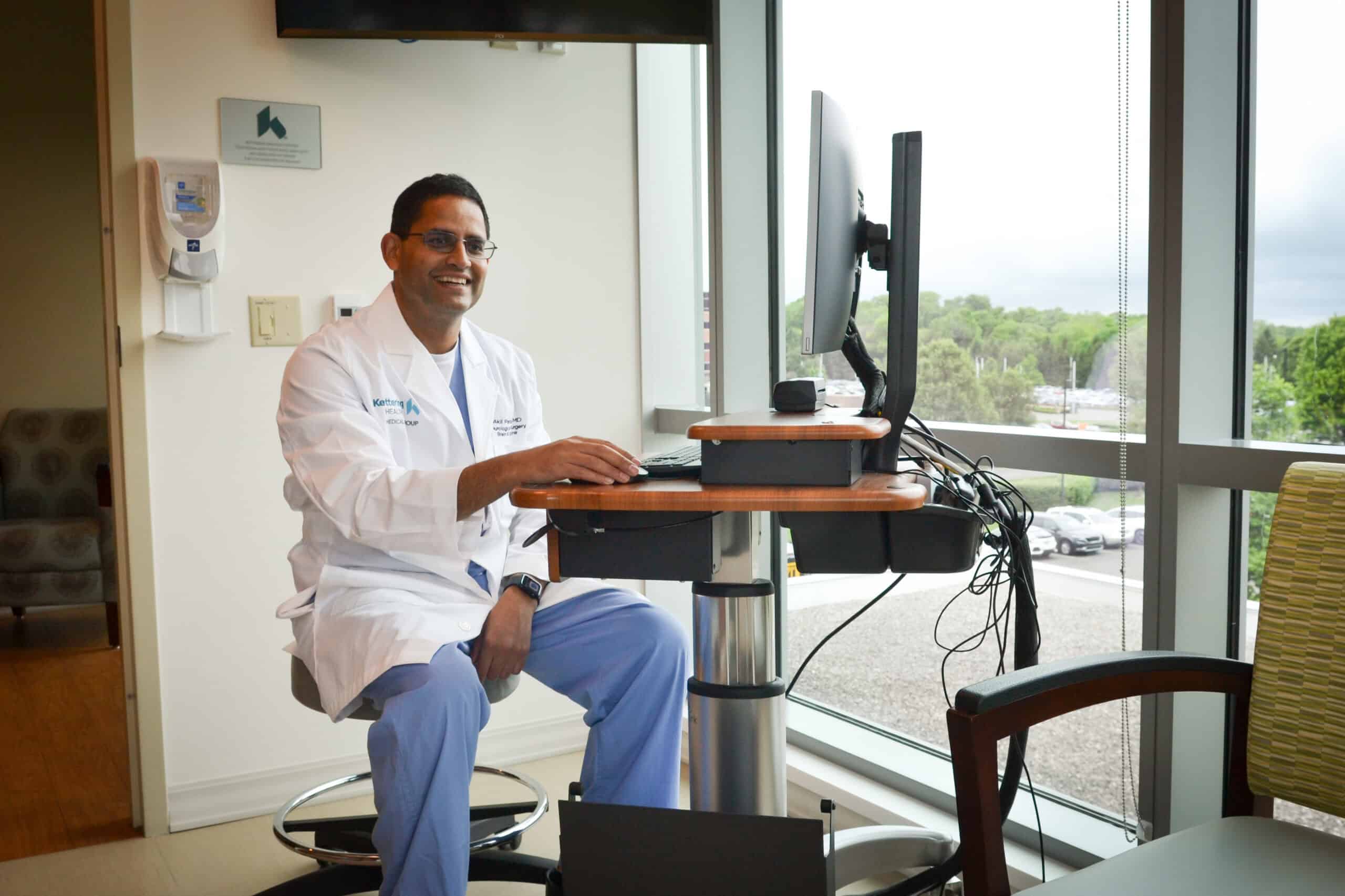 Dr. Patel sitting at a computer in front of a window