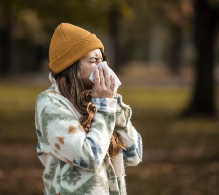 Woman sneezing in handkerchief at autumn