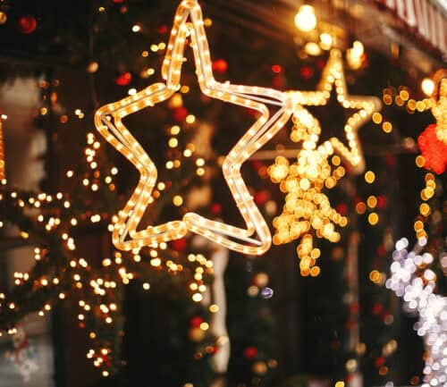 Golden star-shaped Christmas lights with colorful bokeh holiday decorations on city street