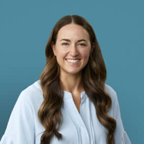 Professional headshot of Dr. Abby Hinkel smiling in white blouse against blue background