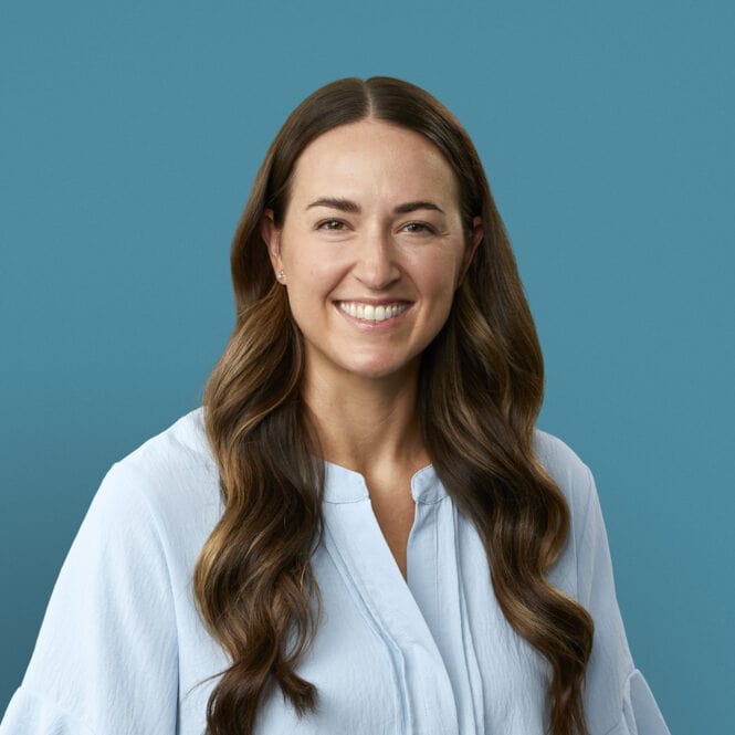 Professional headshot of Dr. Abby Hinkel smiling in white blouse against blue background