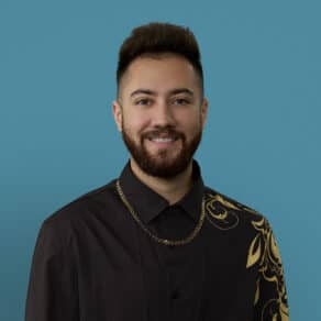 Professional headshot of Dr. Aelius Khan smiling in black shirt with gold chain