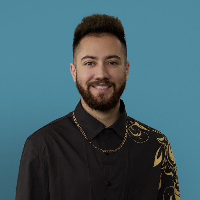 Professional headshot of Dr. Aelius Khan smiling in black shirt with gold chain