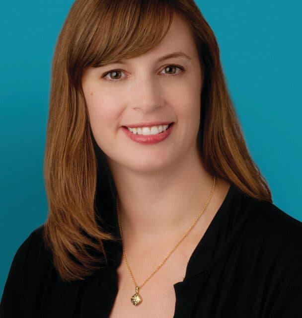 Professional headshot of Dr. Aimee G. Russell smiling against turquoise background