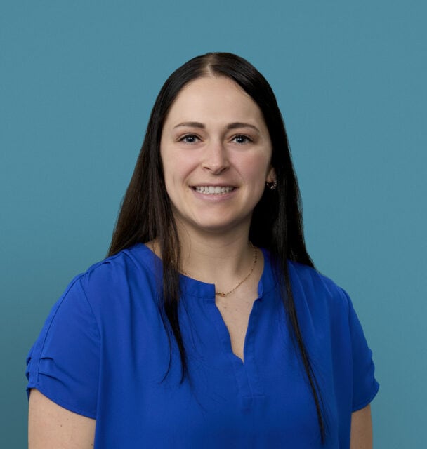 Professional headshot of Alyssa Vactor, APRN-CNP, smiling in blue medical scrubs