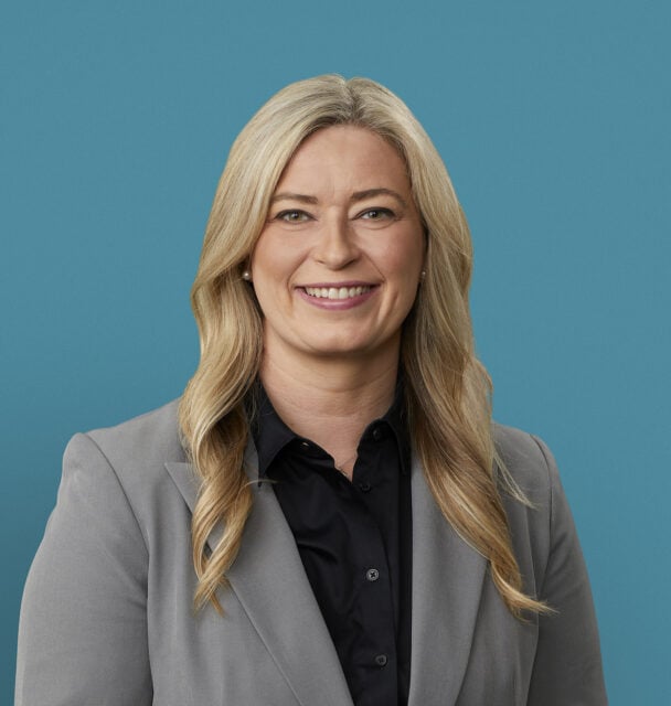 Professional headshot of Amber Orellana, APRN-CNP in gray blazer and black shirt