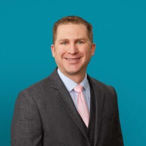 Professional headshot of Andrew D. Galusha, MD in gray suit with pink tie