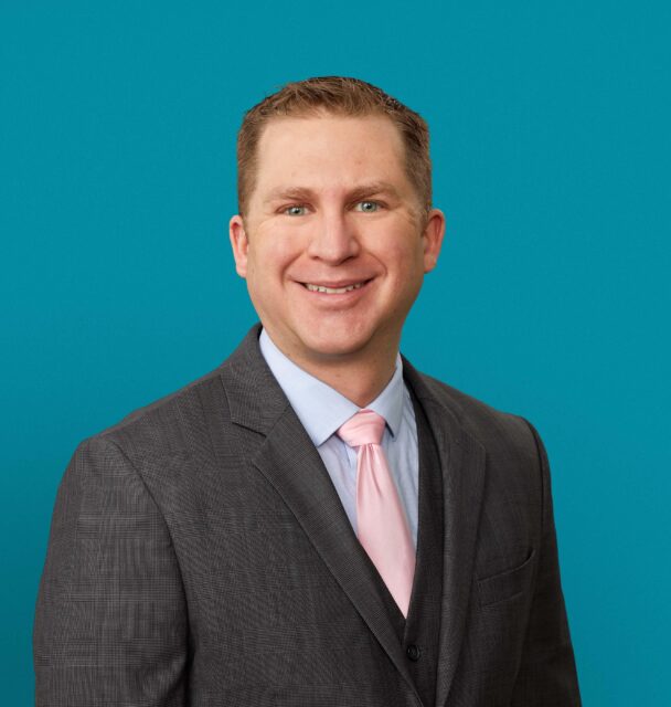 Professional headshot of Andrew D. Galusha, MD in gray suit with pink tie
