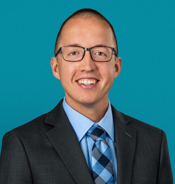Professional headshot of Dr. Andrew Fellers in dark suit and blue tie