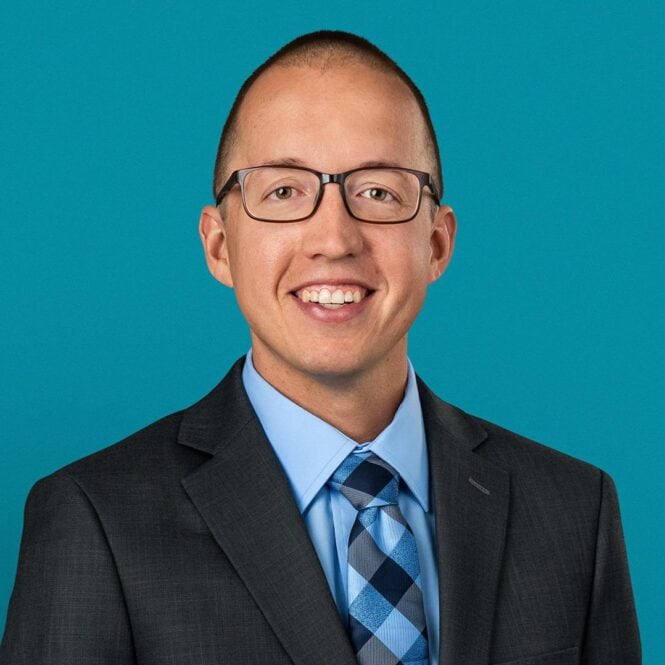 Professional headshot of Dr. Andrew Fellers in dark suit and blue tie