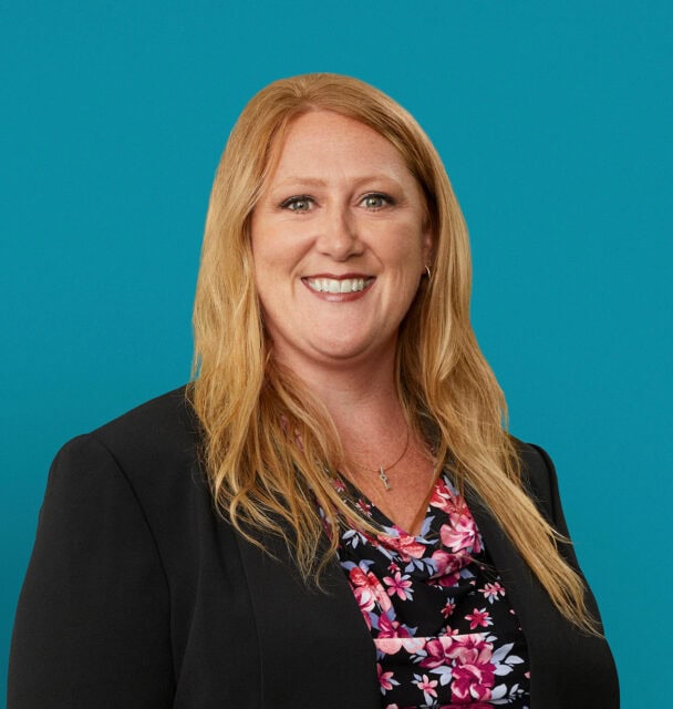 Professional headshot of Angela Keeton, APRN-CNP, smiling in black blazer against turquoise background