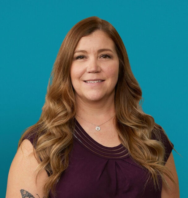 Professional headshot of Angela M. Bartlett, APRN-CNP in purple top against teal background