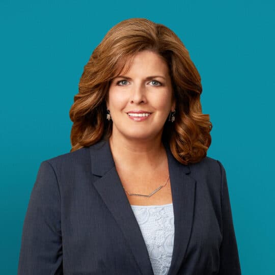 Professional headshot of Angela R. Paugh, APRN-CNP in navy blazer against teal background