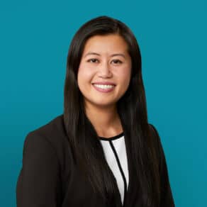 Professional headshot of Anh Dao Le, PharmD smiling in dark blazer against teal background