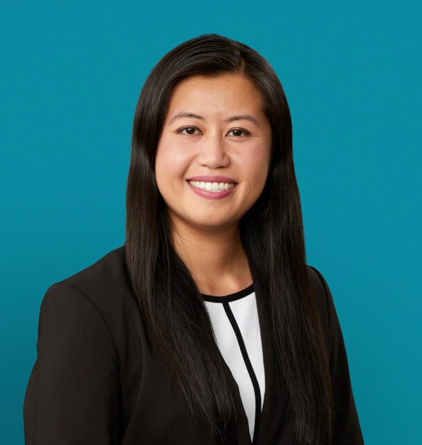 Professional headshot of Anh Dao Le, PharmD smiling in dark blazer against teal background