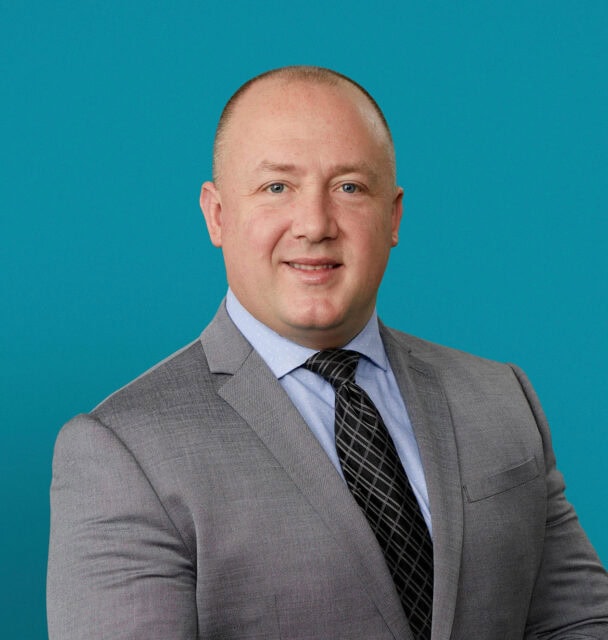 Professional headshot of Anthony Blanchard, DPM in gray suit against teal background